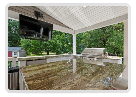 Outdoor kitchen featuring granite countertops, stainless steel appliances, and a television for entertainment.