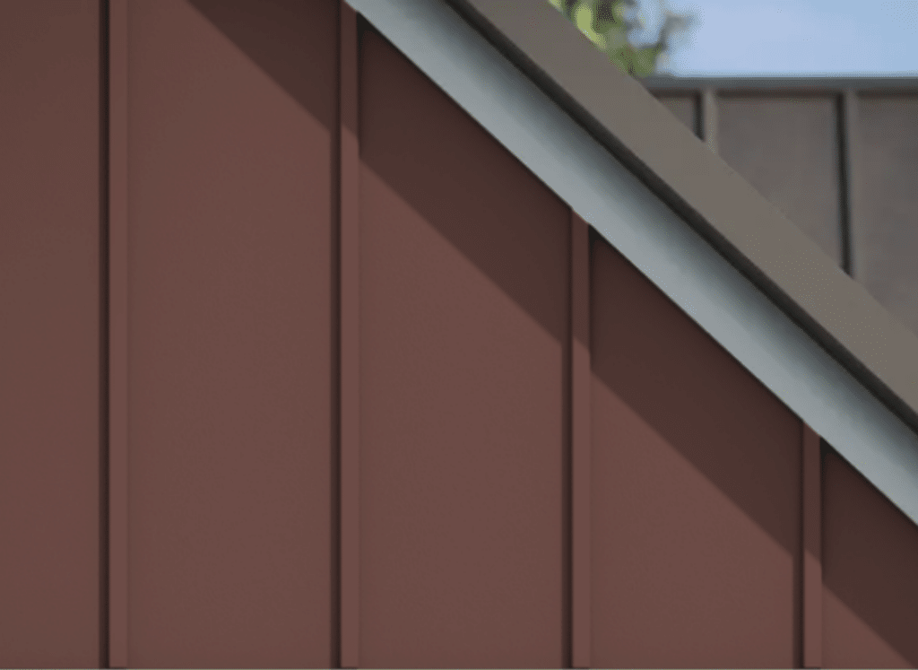 A close-up view of a house’s exterior featuring deep red fiber cement siding with a vertical board and batten design. The siding panels are smooth and evenly spaced, with contrasting trim along the roofline. Sunlight casts soft shadows on the surface, emphasizing the texture and durability of the material.