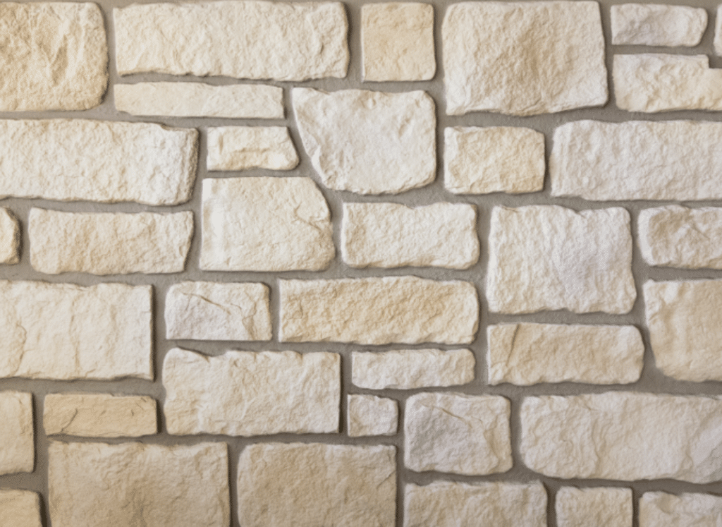 A close-up view of a limestone stone siding wall featuring irregularly shaped, cream-colored stones with a rough texture, arranged in a natural pattern with visible mortar lines.