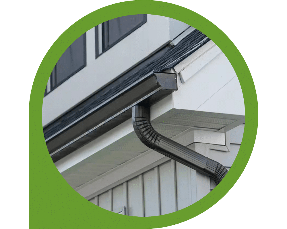 Black seamless gutter and downspout installed on modern home exterior.